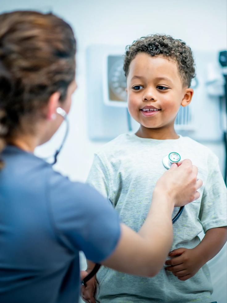 A female NYU Grossman Long Island School of Medicine student uses a stethoscope to hear a young boy's heart beat.