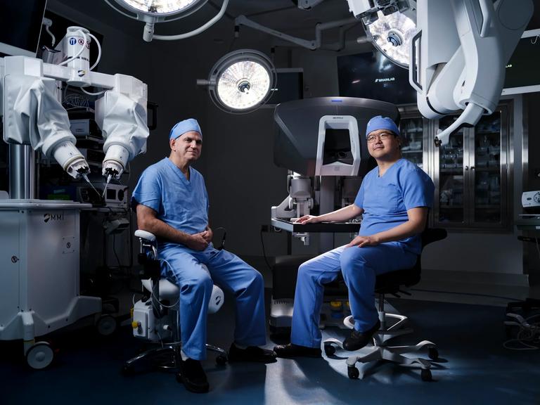 Jamie P. Levine, MD, left, and Lee C. Zhao, right, sit together in an operating room surrounded by robotic equipment.