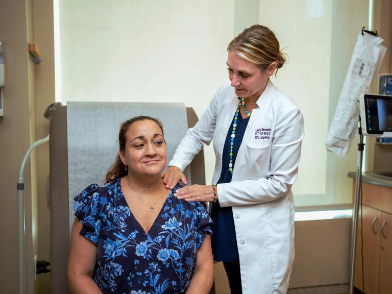 Laurie J. Wennerholm, right, stands and conducts a physical exam on a patient, right, seated on an exam bed.