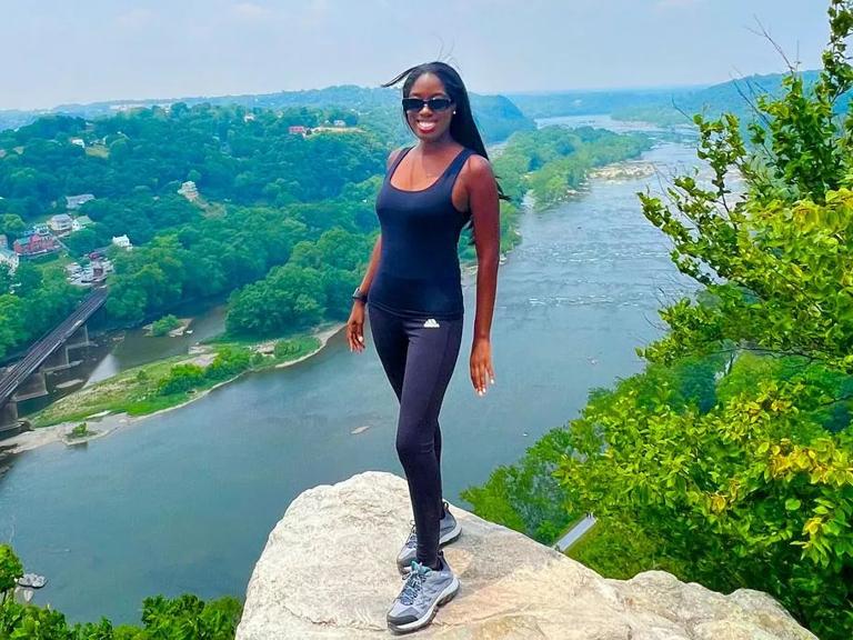 Tiffany Miller stands on the top of a cliff overlooking a river