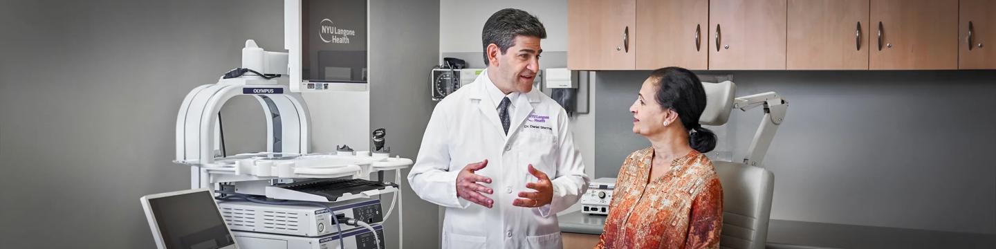 Dr. Daniel H. Sterman speaks with a female patient in an examing room.
