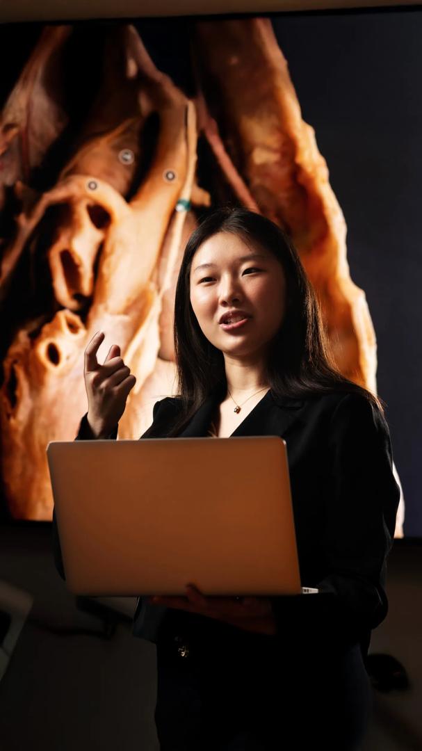 Lily Ge, a student at NYU Grossman School of Medicine, sits next to AI-driven web tools on her laptop showing amplified anatomical images.