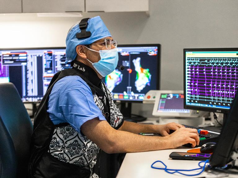 Lior Jankelson, MD, PhD, monitors cardiac mapping and electrophysiology data across several computer screens while seated.
