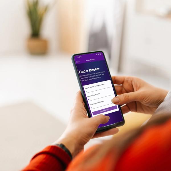 Photography of two hands holding their mobile phone, which displays the NYU Langone's Find-a-Doctor tool.