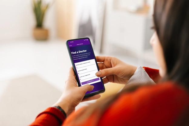 Photography of two hands holding their mobile phone, which displays the NYU Langone's Find-a-Doctor tool.