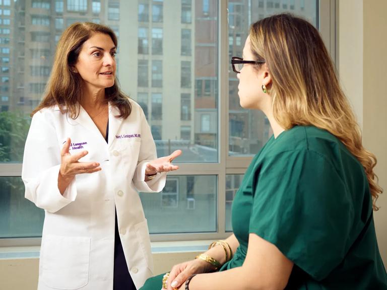 Mary Gemignani, MD, left, stands while talking to a female patient, right.