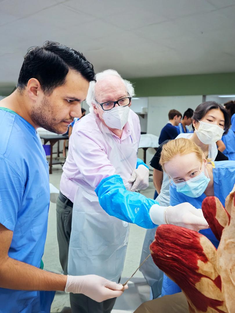 Mel Rosenfeld, PhD, center, points to an anatomical structure while teaching two female students and a male student at the Anatomy Lab at NYU Grossman School of Medicine.