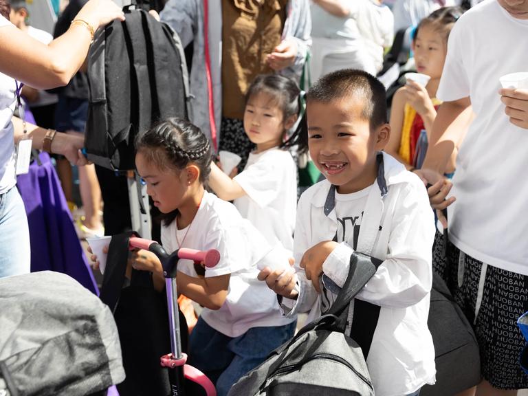 A group of children stand with a large group.
