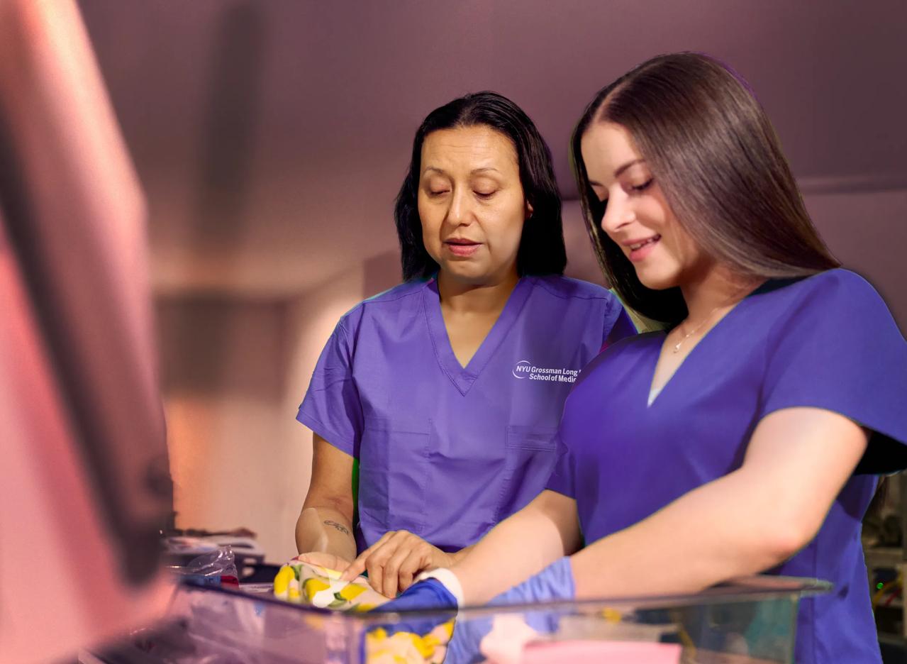 Sonia Gil (left) and Jaclyn Mellone fold blankets at NYU Langone Hospital &ndash; Long Island NICU with fellow unit nursing staff.