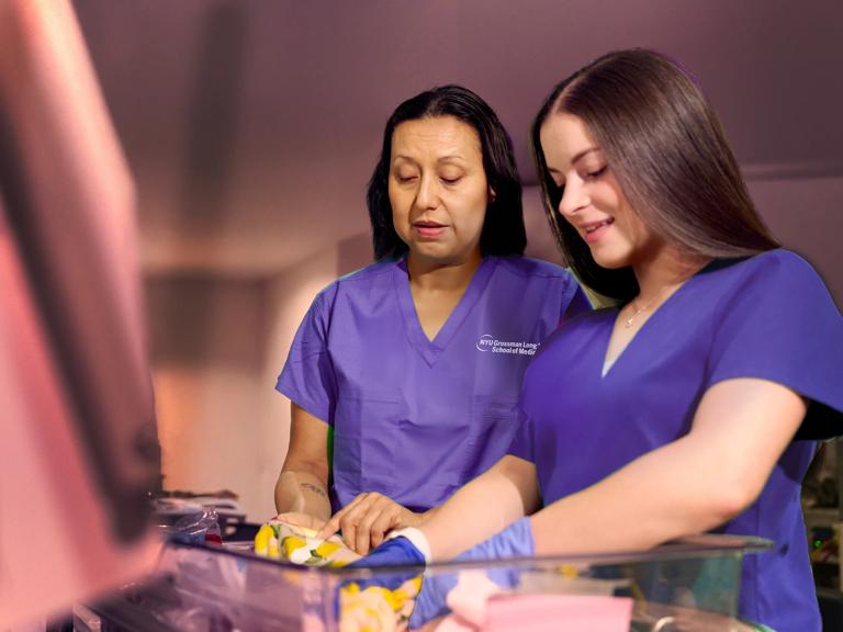Sonia Gil (left) and Jaclyn Mellone fold blankets at NYU Langone Hospital &ndash; Long Island NICU with fellow unit nursing staff.