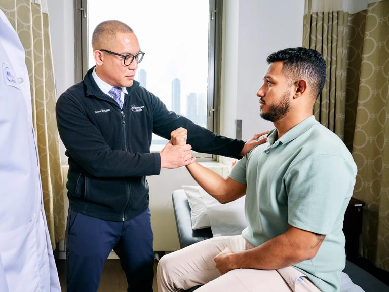 Salvador Portugal, DO, left, examines a patient at NYU Langone Orthopedic Center.