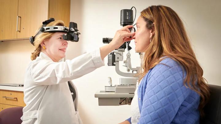 Laura Balcer, MD, left, conducts an exam on a female patient, right, seated.