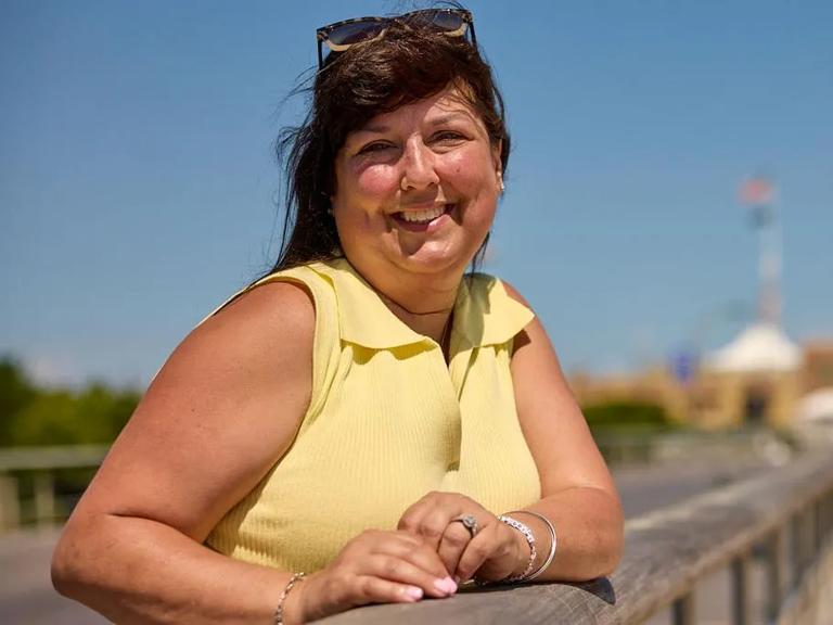 A woman smiles on a boardwalk.