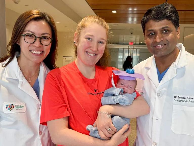 Reina Tan, MD, left, Sarah Oliveri, center, and T.K. Susheel Kumar, MD, right, stand together in the Congenital Cardiovascular Unit at NYU Langone Health. Oliveri holds her baby, Mikey Oliveri.