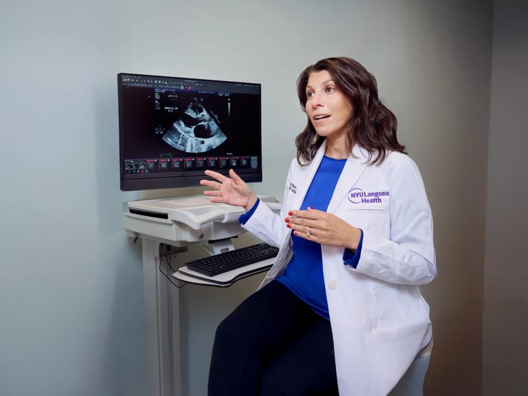Michelle Bloom, MD, explains the results of an ultrasound image on a monitor in a patient room.