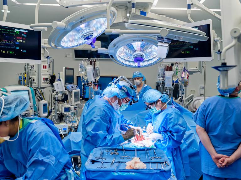 Dr. Robert Montgomery and team performing xenotransplant surgery in equipment-filled operating room.