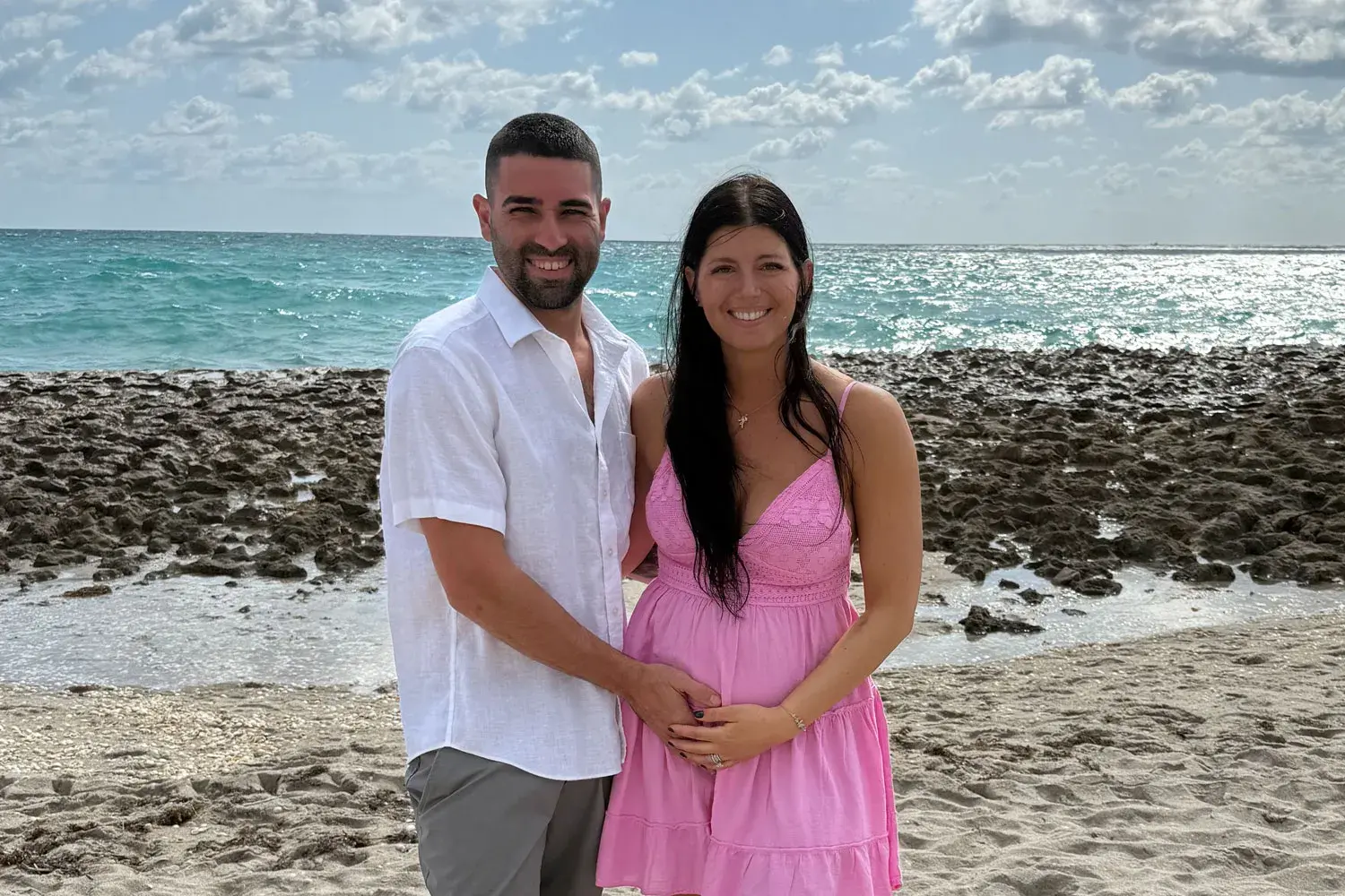 A man, left, and a woman, right, stand next to each other on a beach.