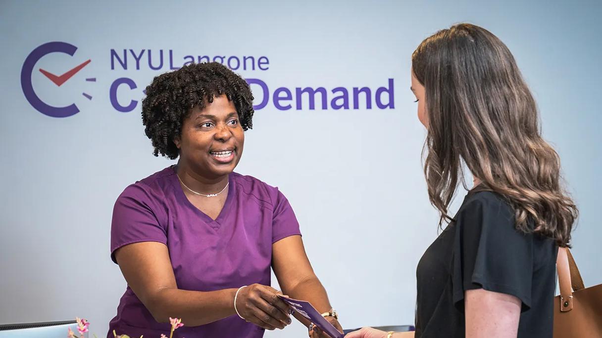 An NYU Langone emnployee hands a brochure to a patient at a Care on Demand location in Manhattan.