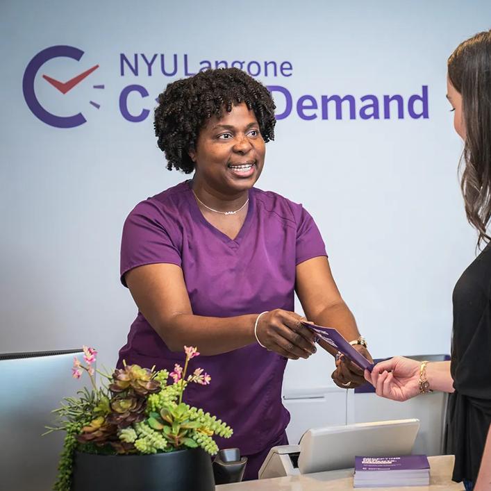 An NYU Langone emnployee hands a brochure to a patient at a Care on Demand location in Manhattan.