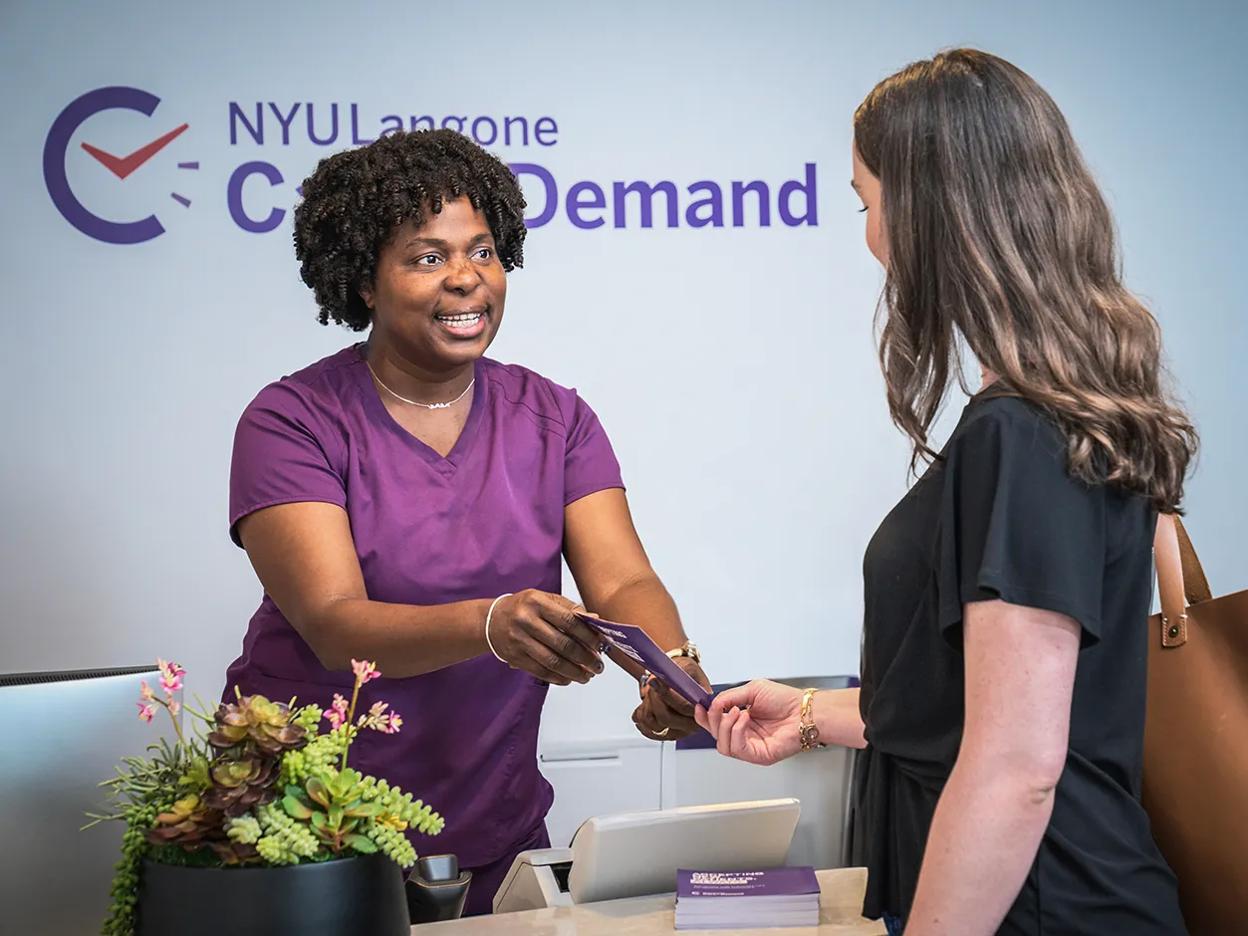 An NYU Langone emnployee hands a brochure to a patient at a Care on Demand location in Manhattan.