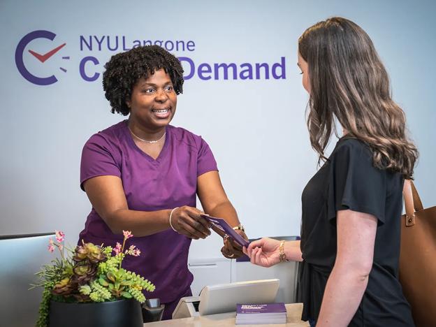 An NYU Langone emnployee hands a brochure to a patient at a Care on Demand location in Manhattan.