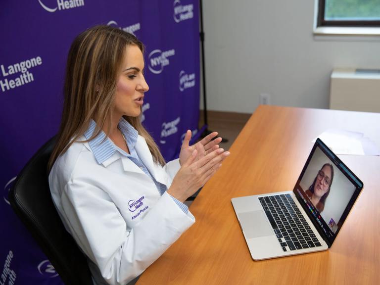 A female doctor, left, sits and speaks to to a patient through a computer, right.