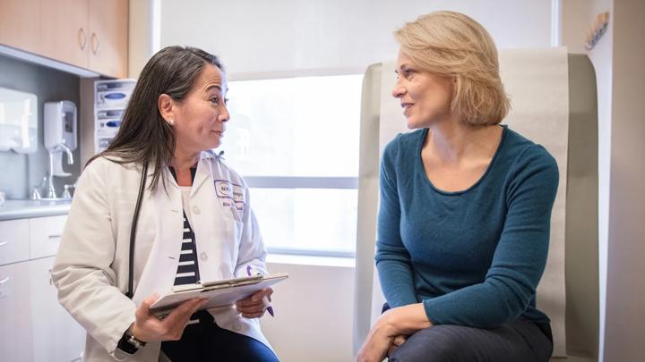 Nila De La Rosa, left, sits in an exam room with a female patient, right.