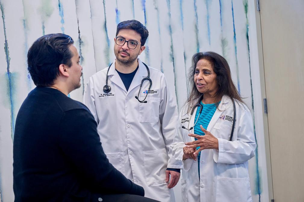 2 doctors and a patient talk in an exam room. 