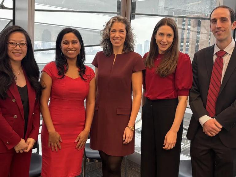 Doctors Harmony Reynolds, Anais Hausvater, Shaline Rao, Doris Chan, and Nathaniel Smilowitz, dressed in red, stand together in an office.